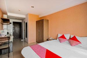 a bedroom with a bed with red and white pillows at Hotel O Tridasa in Medan