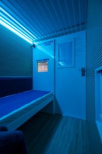 a blue room with a bench in a room with a door at Resting Pods - -ZZZleepandGo MXP Airport in Ferno