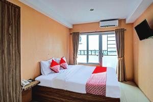 a bedroom with a bed with red pillows and a window at Hotel O Tridasa in Medan