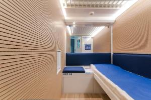 Zimmer mit einer blauen Bank und einer Wand in der Unterkunft Resting Pods - -ZZZleepandGo MXP Airport in Ferno