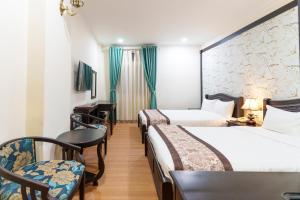 a hotel room with two beds and a desk and chairs at Royal Dalat Hotel in Da Lat