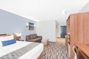 a hotel room with a bed and a chair at Microtel Inn & Suites by Wyndham Binghamton in Binghamton