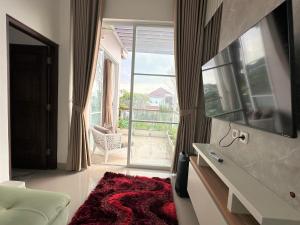a living room with a large window and a red rug at Moses Homestay, Yogyakarta in Beran-kidul