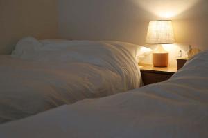 a bedroom with two white beds and a lamp at The Cabin by Deep Gorge in Kita-karuizawa