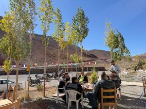 a group of people sitting at a table in a yard at Auberge Restaurant Oumidou in Agoudal