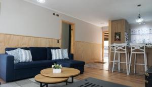 a living room with a blue couch and a table at Lodge Perry Barnes in Puerto Varas