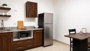 a kitchen with a stainless steel refrigerator and a table at Lumina loft express minutes to consulate in Hermosillo