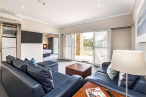 a living room with a blue couch and a table at Caves House Apartments Yallingup in Yallingup