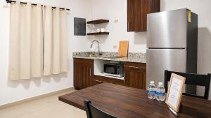a kitchen with a table and a stainless steel refrigerator at Lumina loft express minutes to consulate in Hermosillo