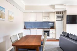 a kitchen and dining room with a wooden table and chairs at Caves House Apartments Yallingup in Yallingup +23 photos