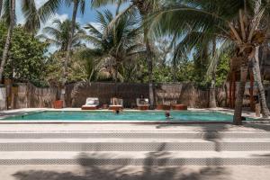 a swimming pool with palm trees in the background at Nílu Isla Mujeres by Selina in Isla Mujeres +50 photos
