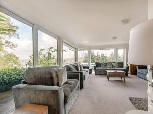 a living room with couches and chairs and windows at Five Bays View in Aberporth