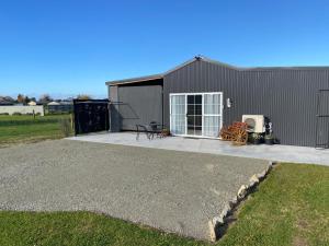 a large gray building with a patio in front of it at The Jam Shed in Waimate