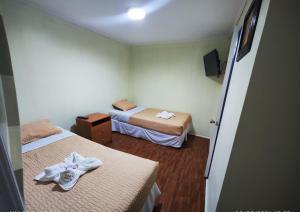 a room with two beds with towels on them at Hostal San Lorenzo in Iquique