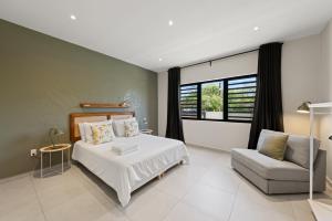 a bedroom with a bed and a chair and a window at Villa Anosia Laman i Tera in Westpunt