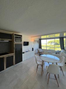 a living room with a table and a kitchen at Le Studio de la Lagune studio cabine proche de la plage in Le Grau-du-Roi