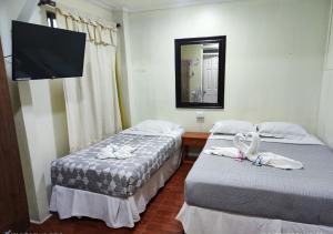 two beds in a room with a mirror and a tv at Hostal San Lorenzo in Iquique +8 photos