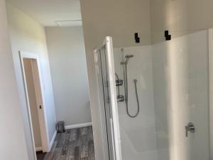 a bathroom with a shower with a glass door at The Jam Shed in Waimate +8 photos