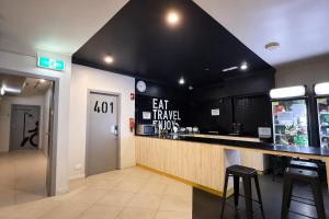a bar in a restaurant with black walls and stools at Space Q Capsule Hotel in Sydney