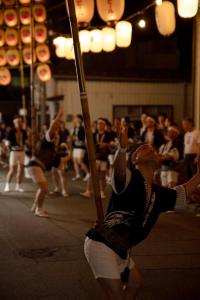 a man is holding onto a pole in a performance at goemon-inn in Akita