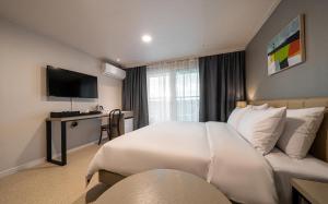 a bedroom with a large white bed and a desk at Hotel Corner Inn in Pyeongtaek