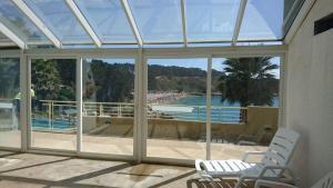 a conservatory with a view of a swimming pool through windows at Algarrobo, Pinares de Canelillo in Algarrobo