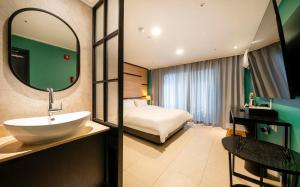 a bathroom with a sink and a bed in a room at Hotel Corner Inn in Pyeongtaek