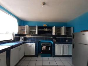 a kitchen with blue walls and white cabinets and a refrigerator at Amplio y cómodo departamento. in Loja +8 photos