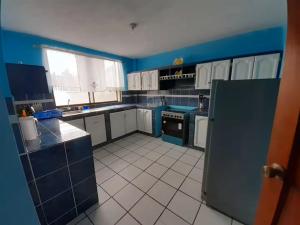 a large kitchen with blue walls and white cabinets at Amplio y cómodo departamento. in Loja