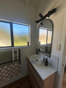 a bathroom with a sink and a mirror at Coastal Escape - Cooks Beach in Cooks Beach +7 photos