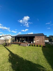a house with a large yard with a grass field at Coastal Escape - Cooks Beach in Cooks Beach