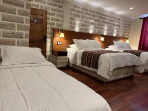 a bedroom with two beds and a brick wall at Hotel de Sal Atipax in Uyuni