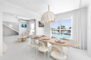 a white dining room with a table and chairs at WhitsunStays - The Cyclades in Eimeo