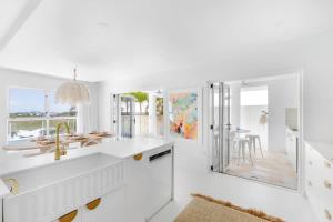 a white kitchen with a sink and a dining room at WhitsunStays - The Cyclades in Eimeo