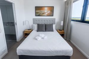 a bedroom with a white bed with two towels on it at WhitsunStays - The Regal (2br/2bth, Central) in Mackay +3 photos