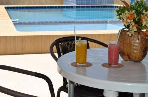 duas bebidas numa mesa ao lado de uma piscina em Pousada Espaço Litoral em Baixio