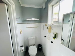 a small bathroom with a toilet and a window at White Manor Motel in Cooma +62 photos