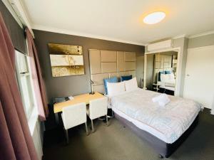 a bedroom with a bed and a desk with a table at White Manor Motel in Cooma