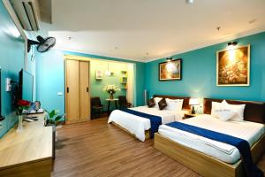 two beds in a room with blue walls at Dream Hotel Hà Nội in Hanoi