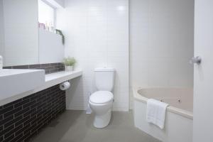 a white bathroom with a toilet and a bath tub at Bay View Sunrise in Lorne +10 photos
