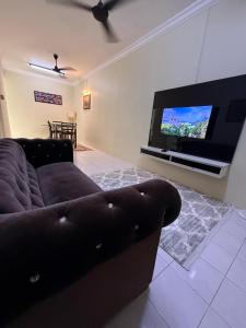 a living room with a couch and a flat screen tv at Lanisa Staycation Mesra in Kampong Padang Bungor