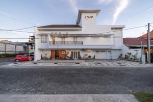 a white building with a car parked in front of it at Cove Amayana in Surabaya
