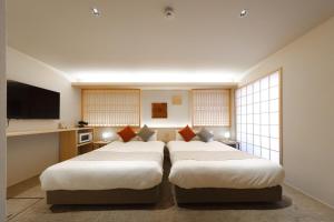 a room with two beds in a room with windows at はく HIROSHIMA Station HOTEL in Hiroshima