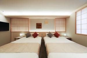 a room with two beds and a flat screen tv at はく HIROSHIMA Station HOTEL in Hiroshima