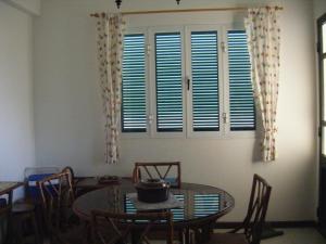 a dining room with a table and chairs and windows at Casa Mansa in Porto Santo
