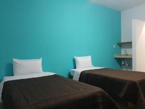 2 camas en una habitación con una pared azul en La Siesta del Patron en Querétaro