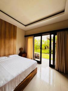a bedroom with a bed and a large window at Guest House Reisya in Nusa Dua