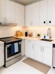 a kitchen with white cabinets and a stove and sink at Sapphire Loft Midtown in Atlanta