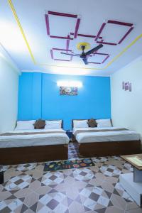 two beds in a room with blue walls and a ceiling at Green Valley Hotel - Srinagar in Srīnagar