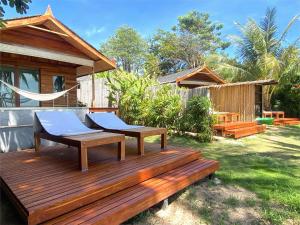 a wooden deck with a hammock in a backyard at Nibbana Bungalows in Hinkong